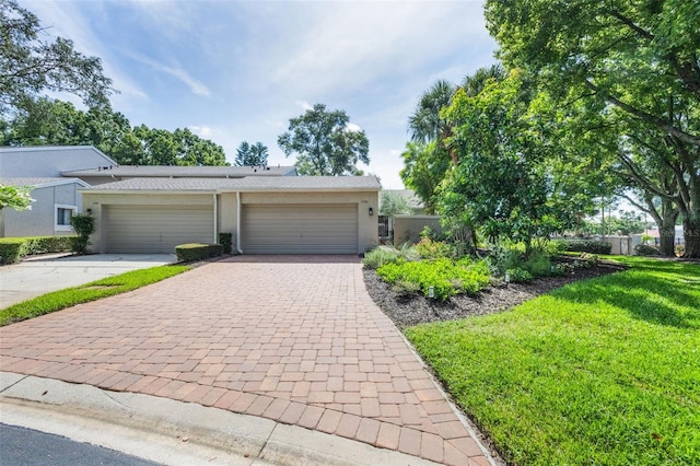 7755 High Pine Rd, Orlando, FL 32819 - view of front of home featuring driveway, stucco siding, a garage, and a front lawn