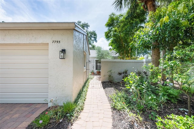 7755 High Pine Rd, Orlando, FL 32819 - view of property exterior with stucco siding and a gate