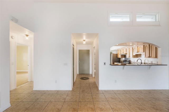7755 High Pine Rd, Orlando, FL 32819 - unfurnished living room featuring a towering ceiling, light tile patterned floors, and arched walkways