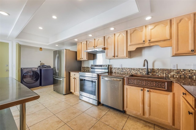7755 High Pine Rd, Orlando, FL 32819 - kitchen featuring appliances with stainless steel finishes, independent washer and dryer, under cabinet range hood, a raised ceiling, and light brown cabinetry