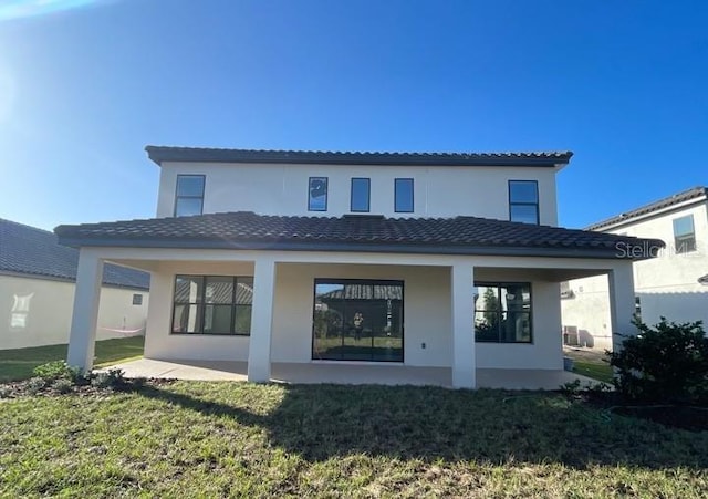 1940 Goblet Cove St, Kissimmee, FL 34746 - back of house featuring stucco siding, a tiled roof, and a lawn