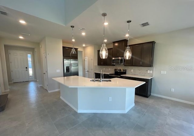 1940 Goblet Cove St, Kissimmee, FL 34746 - kitchen featuring appliances with stainless steel finishes, backsplash, dark brown cabinetry, a kitchen island with sink, and recessed lighting