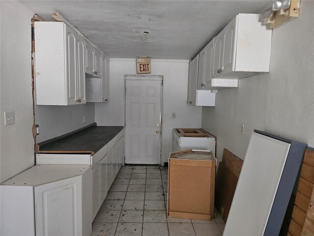 115 N 10th St, Haines City, FL 33844 - kitchen with white cabinetry, light tile patterned flooring, dark countertops, and a textured ceiling