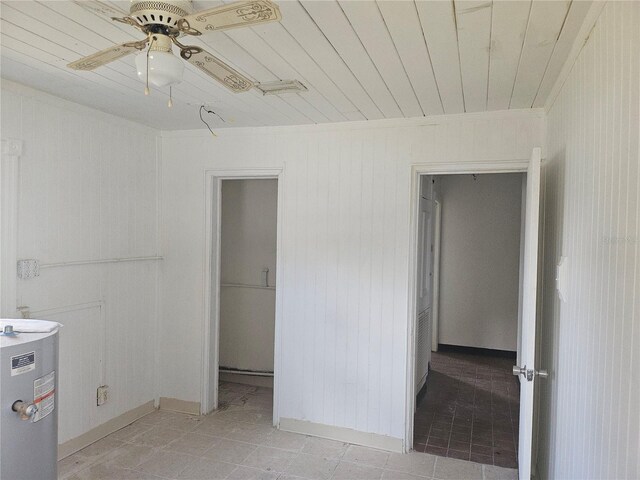 115 N 10th St, Haines City, FL 33844 - spare room with electric water heater, a ceiling fan, wood ceiling, light tile patterned floors, and wooden walls