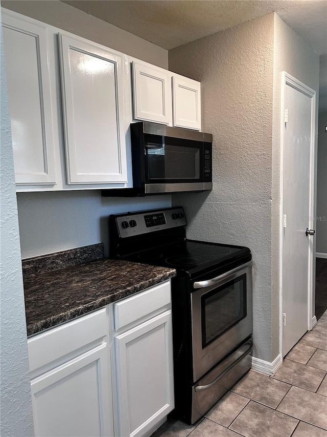 3304 Dew Berry Ave, Apopka, FL 32712 - kitchen featuring stainless steel appliances, white cabinets, a textured wall, light tile patterned floors, and a textured ceiling