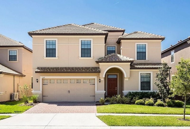 mediterranean / spanish home featuring a garage and a front lawn