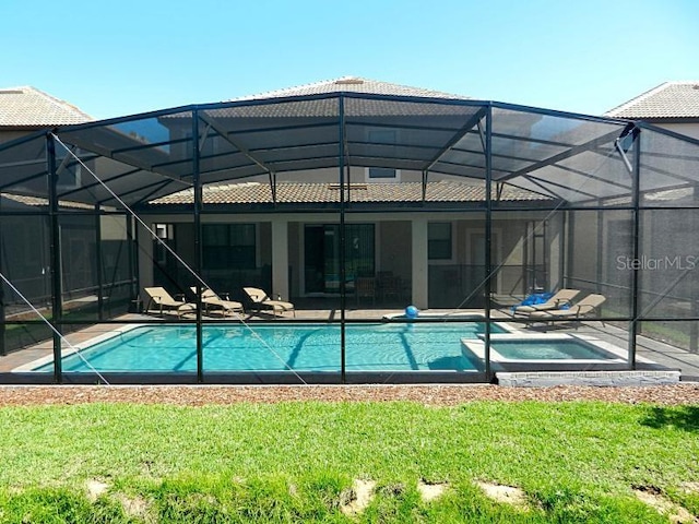 back of house featuring glass enclosure, a yard, and a patio