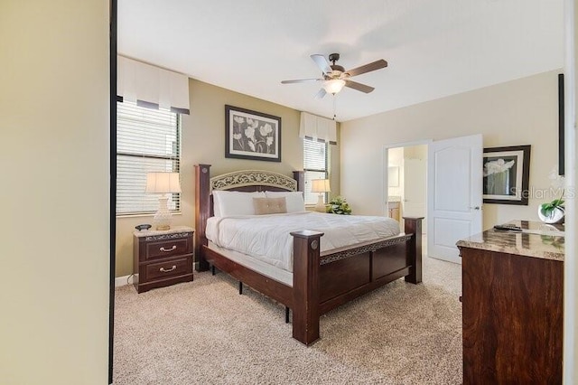 carpeted bedroom with ensuite bathroom and ceiling fan