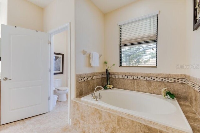 bathroom with tile patterned floors, tiled tub, and toilet