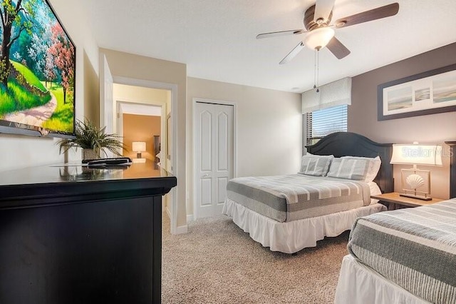 bedroom featuring light colored carpet, ceiling fan, and a closet