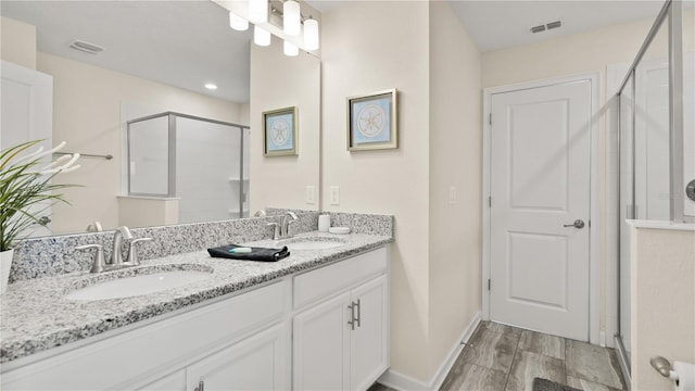 bathroom featuring double vanity, a shower with door, and hardwood / wood-style floors