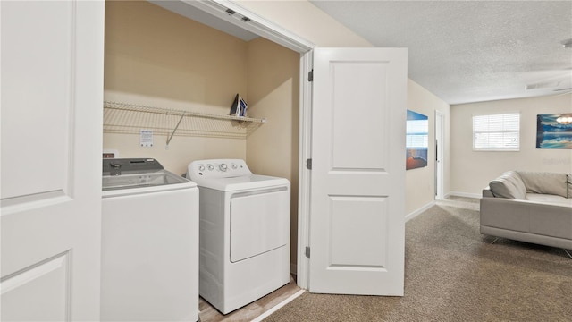 laundry room with a textured ceiling, light colored carpet, and washer and dryer