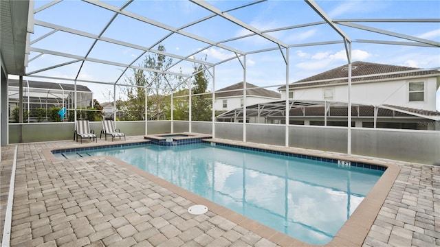 view of swimming pool with glass enclosure, a patio area, and an in ground hot tub