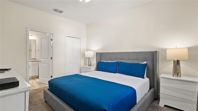 carpeted bedroom with a closet and ensuite bath