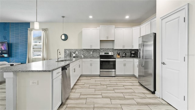 kitchen with sink, hanging light fixtures, appliances with stainless steel finishes, kitchen peninsula, and white cabinets