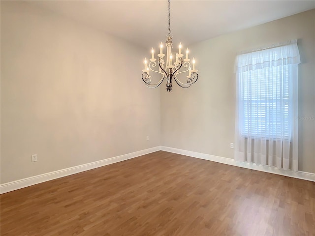 empty room featuring dark hardwood / wood-style flooring and a chandelier