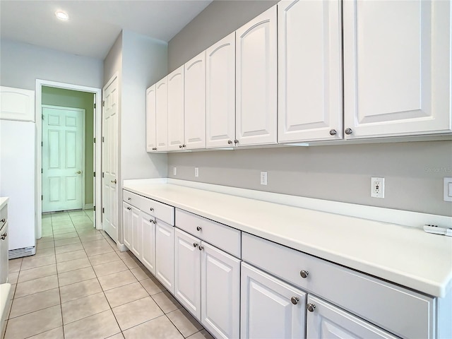 kitchen featuring white cabinetry, light tile patterned floors, and refrigerator