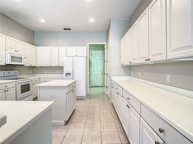 kitchen featuring light tile patterned floors, white appliances, a center island, and white cabinets