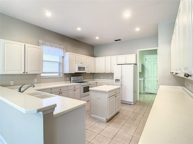 kitchen featuring sink, white appliances, light tile patterned floors, white cabinetry, and a kitchen island