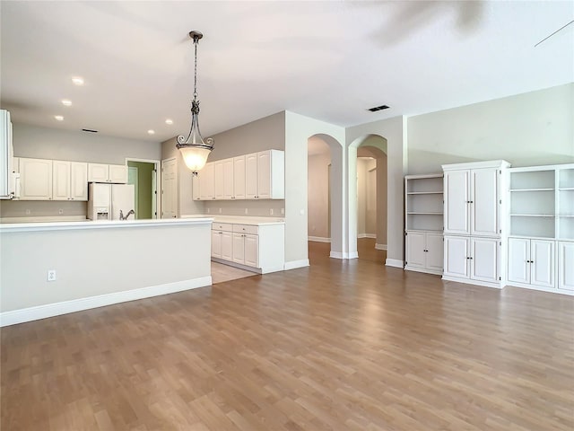 kitchen featuring white cabinetry, decorative light fixtures, white refrigerator with ice dispenser, and light hardwood / wood-style flooring