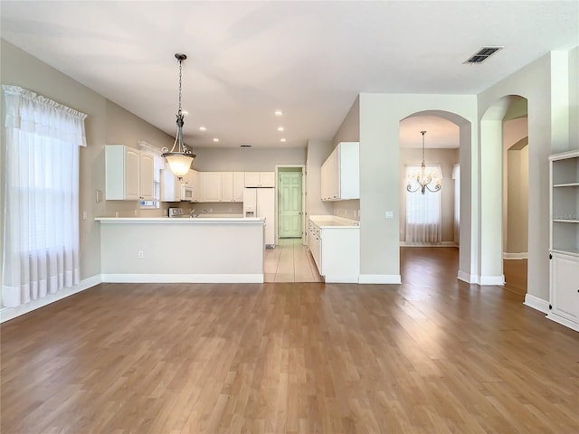 kitchen featuring white cabinetry, decorative light fixtures, light wood-type flooring, kitchen peninsula, and white appliances