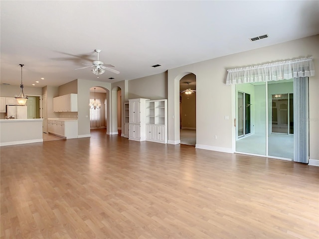 unfurnished living room featuring ceiling fan with notable chandelier and light hardwood / wood-style floors