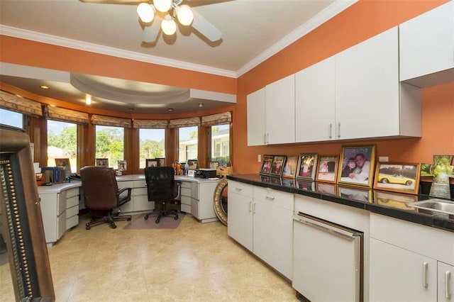 kitchen with a raised ceiling, ceiling fan, white cabinetry, and crown molding