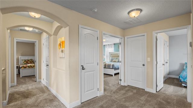 corridor with carpet floors and a textured ceiling