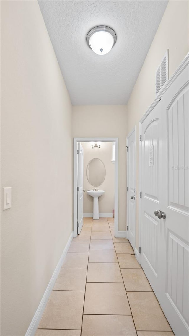 corridor featuring light tile patterned flooring and a textured ceiling