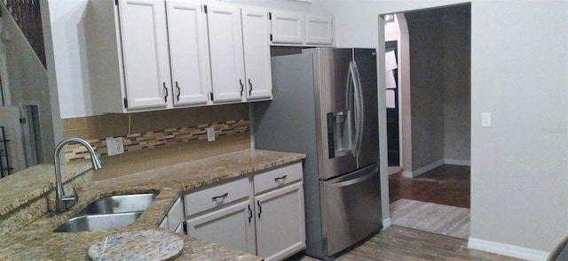 kitchen with white cabinetry, light stone countertops, and sink