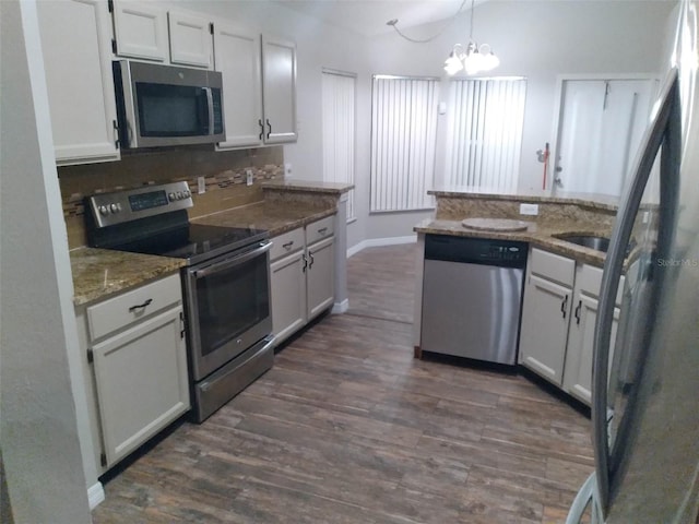 kitchen featuring appliances with stainless steel finishes, white cabinetry, hanging light fixtures, dark stone countertops, and dark hardwood / wood-style floors