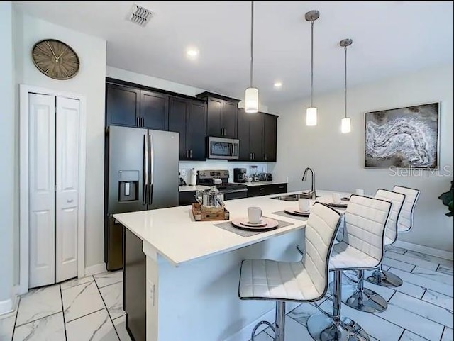 kitchen with a kitchen bar, sink, an island with sink, and stainless steel appliances