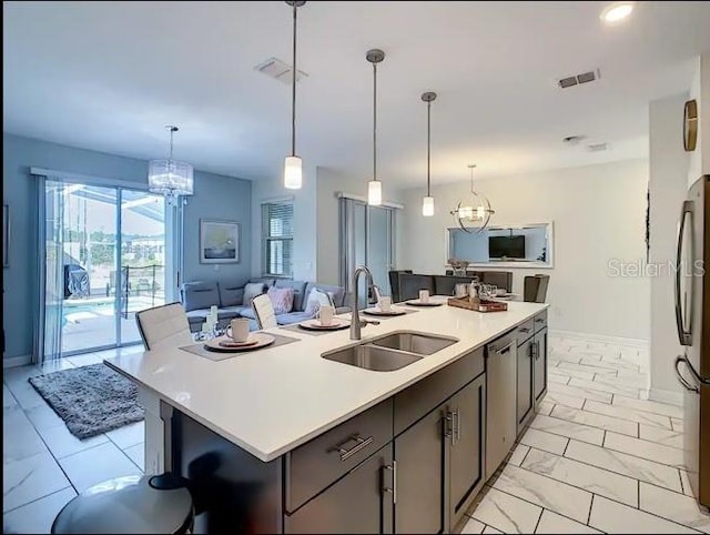 kitchen featuring sink, decorative light fixtures, a center island with sink, and appliances with stainless steel finishes