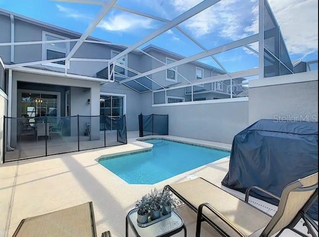 view of swimming pool featuring glass enclosure and a patio area