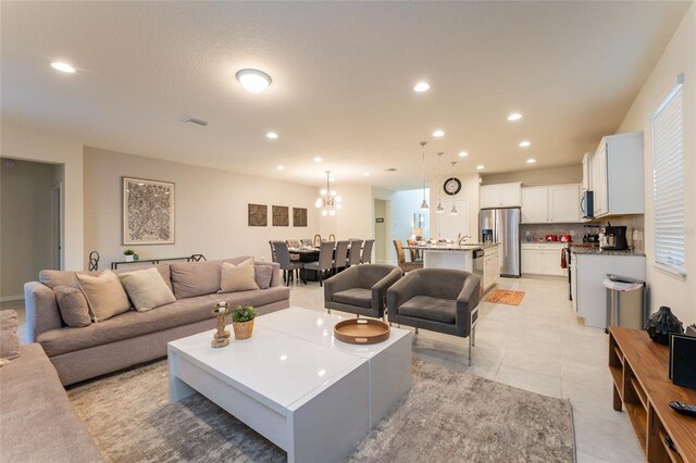 living room with sink, a chandelier, and light tile flooring