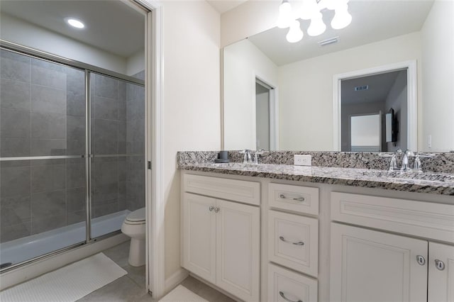 bathroom with double sink vanity, tile floors, a shower with door, and toilet