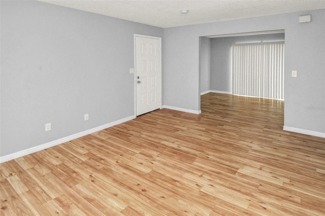 spare room with a textured ceiling and light wood-type flooring