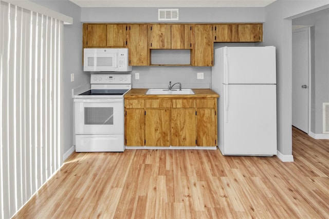 kitchen featuring white appliances, sink, and light wood-type flooring