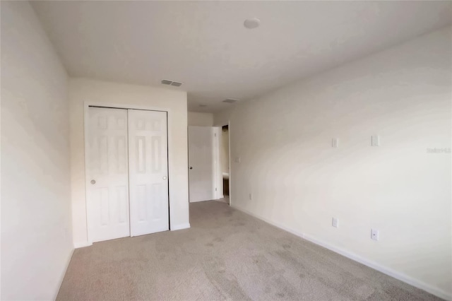 unfurnished bedroom featuring light carpet and a closet