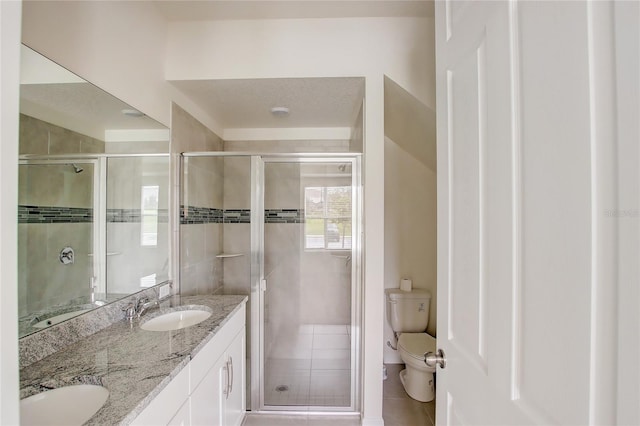 bathroom featuring a textured ceiling, an enclosed shower, toilet, vanity, and tile patterned flooring