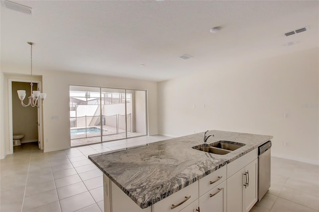 kitchen with sink, dishwasher, stone countertops, white cabinets, and a kitchen island with sink