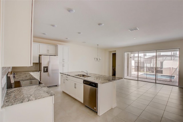 kitchen featuring an island with sink, appliances with stainless steel finishes, white cabinetry, sink, and light stone counters