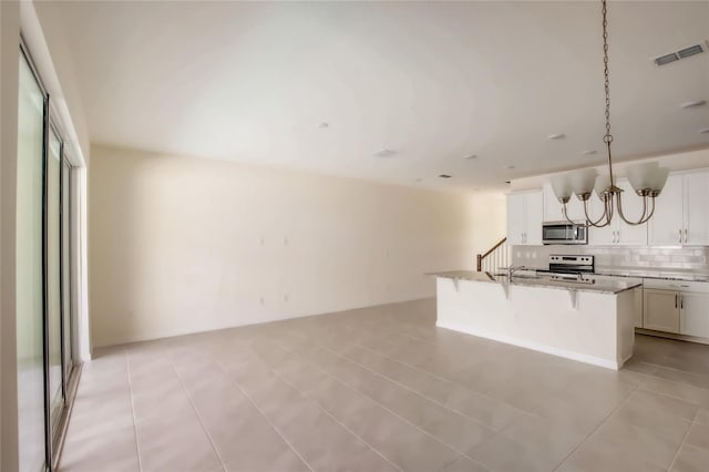 kitchen featuring tasteful backsplash, hanging light fixtures, a center island with sink, a kitchen bar, and stainless steel appliances