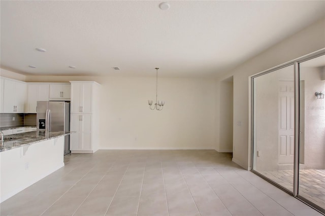 kitchen with stone counters, backsplash, white cabinetry, decorative light fixtures, and stainless steel fridge with ice dispenser