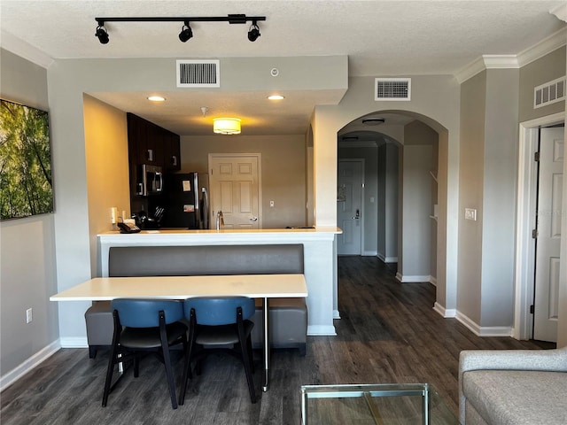 kitchen with black fridge, dark hardwood / wood-style floors, a breakfast bar, and kitchen peninsula