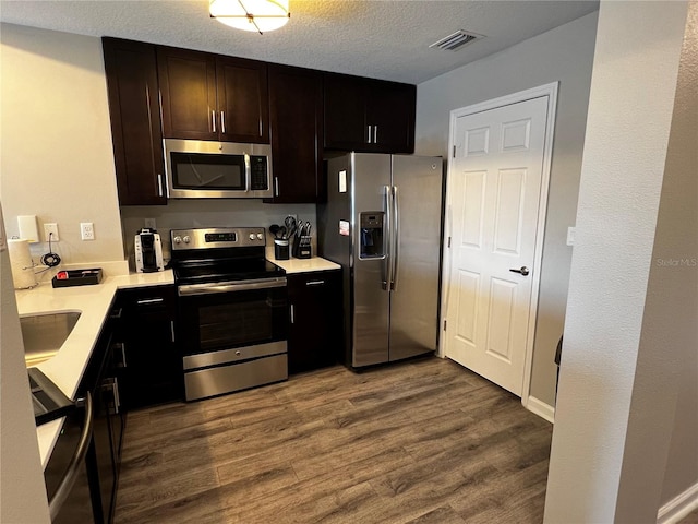 kitchen with hardwood / wood-style floors, a textured ceiling, sink, and stainless steel appliances