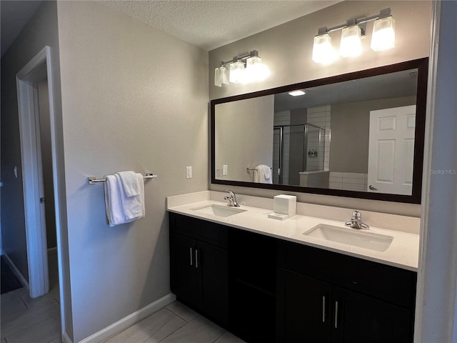 bathroom featuring vanity, tile patterned flooring, a shower with shower door, and a textured ceiling