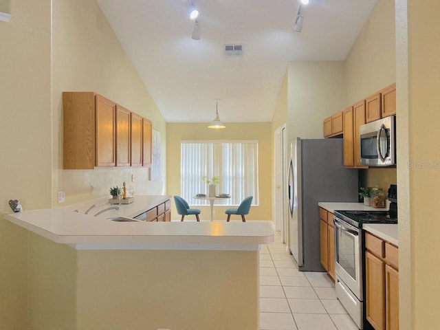 kitchen with appliances with stainless steel finishes, track lighting, sink, light tile floors, and vaulted ceiling