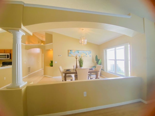 carpeted dining area featuring a chandelier, vaulted ceiling, and decorative columns