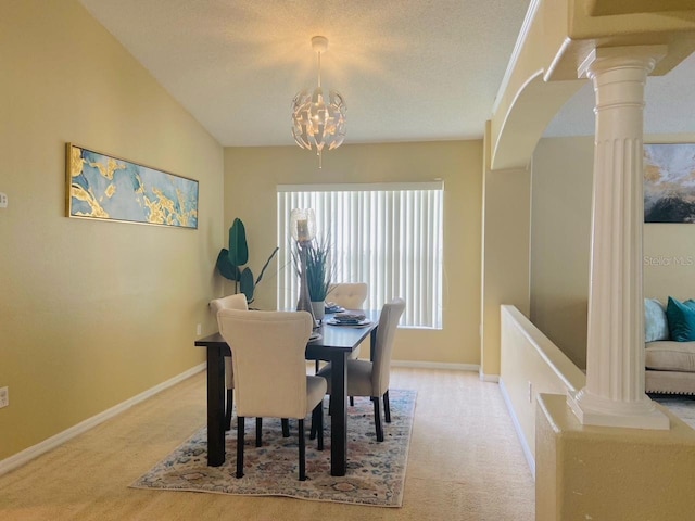 dining area featuring a textured ceiling, light colored carpet, a chandelier, and ornate columns